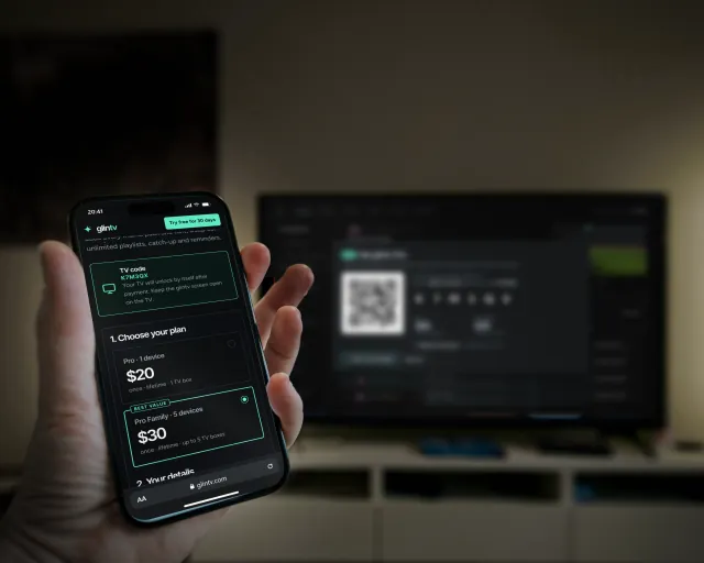 A phone showing the glintv Pro checkout in front of a TV showing a QR code